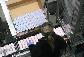 Smyth employee inspecting tubes for quality after decoration.